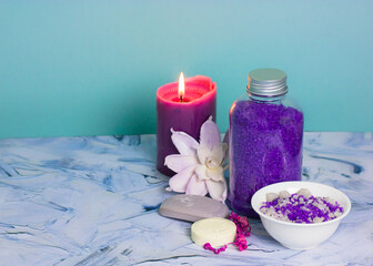 Obraz na płótnie Canvas Composition with a jar of purple lavender sea salt, soap bar, burning lilac candle and beautiful flower. Spa procedure, body, facial care. Cosmetic products. Bathing treatments in a beauty salon.