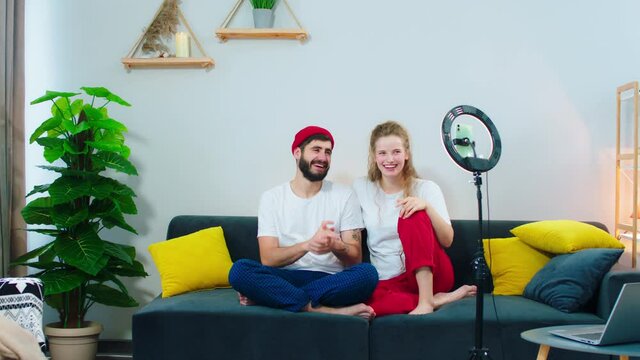 Attractive young couple at home in living room make a live stream they talking about something for the social media account using a light ring for the stream