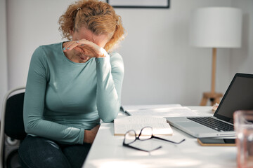 Woman with stomach spasm, cramp, headache, head pain, working from home troubles and issues.