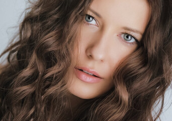 Beauty, hair care and natural makeup look. Beautiful woman with long light brown wavy curls...