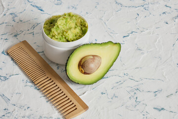 cut in half avocado and wooden comb on light background