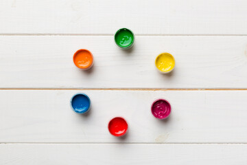 jars with gouache of different colors on Colored background. hobby painting. Top view with empty space. workplace for creativity. home teaching concept drawing