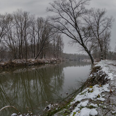 Winter landscape of Ukrina river, snowy banks and naked trees in riparian zone