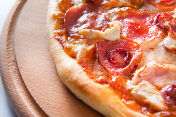 meat pizza lies on a wooden round board on a white background, close-up