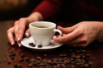 Coffee cup and coffee beans on table, wooden background, hands with a white cup of coffee, cafeteria