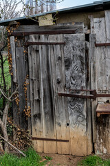 Porte d'une cabane ancienne noircie par le temps dans un petit jardin 