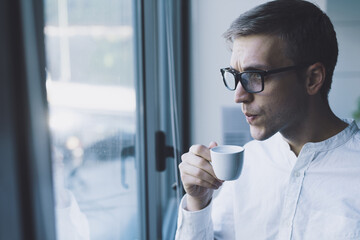 Man having a coffee break next to a window