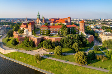Krakow, Poland. Historic royal Wawel castle and cathedral with park and Vistula river. Aerial view at sunset. Old town with St. Mary church in the background. Promenades, walking people and cyclists
