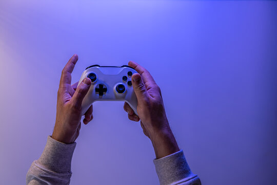 Male hands hold a gamepad on a blue background, copy space. - Powered by Adobe