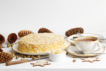 Homemade cake with almond petals and cup of tea on white wooden table. Front view.