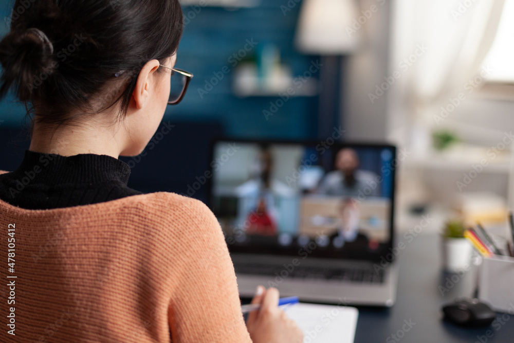 Poster student in group videocall taking notes. over the shoulder view of freelancer having briefing video 
