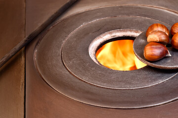 Close-up of some chestnuts on the fire of a wood stove.The photo represents something typical of the autumn season and is shot in horizontal format.