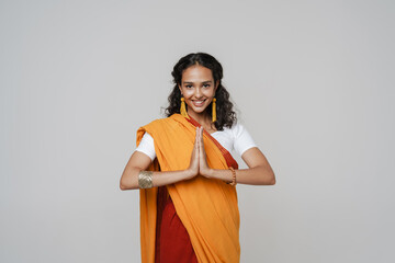 South asian woman wearing sari smiling while making namaste gesture