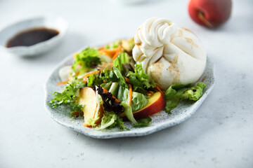 Healthy green salad with peach and burrata cheese