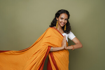 South asian woman wearing sari smiling while making namaste gesture - obrazy, fototapety, plakaty