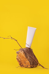 White tube of cream or body lotion on a pieces of stone on a yellow background. Natural cosmetic still life product photo 