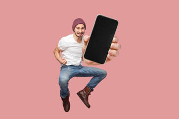 Happy man flying and jumping in air and showing big mobile empty screen for copy space and...