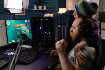 Fototapeta Couple celebrating video games win on live stream. Woman feeling happy about man winning gameplay while he is streaming online with chat on computer. Streamer using gaming equipment obraz