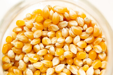 Background photo of dry corn kernels in a glass bowl. Dry golden yellow corn kernels.