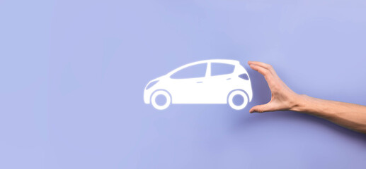 Male hand holding car auto icon on grey background. Wide banner composition.Car automobile insurance and collision damage waiver concepts