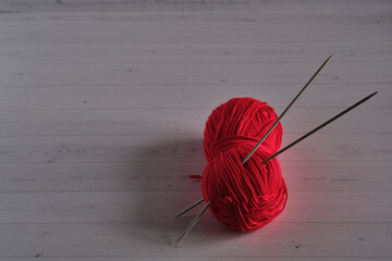 red skein of yarn for knitting and knitting needles, on a light background