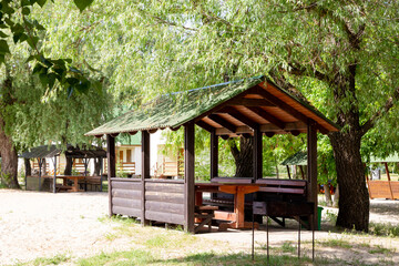 Wooden gazebo under green summer trees exterior