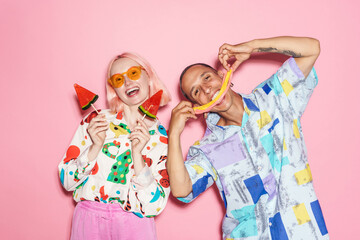 Young couple in multicolored shirts making fun with candies