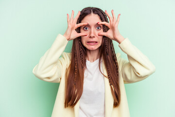 Young caucasian woman isolated on green background keeping eyes opened to find a success opportunity.