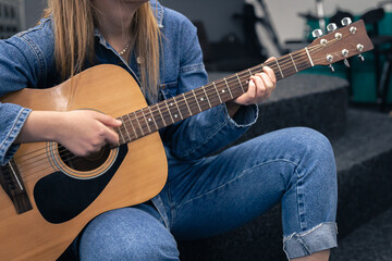 Obraz na płótnie Canvas Close-up, a woman in a denim suit plays the guitar.