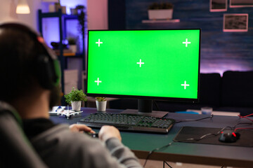 Gamer using horizontal green screen on computer. Man playing video games on chroma key with...