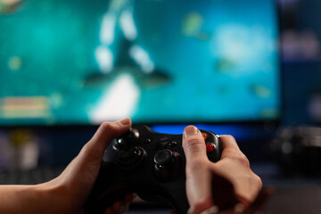 Close up of gamer holding controller and playing video games on computer. Woman using joystick to play online digital games in front of monitor. Person with modern gaming equipment © DC Studio