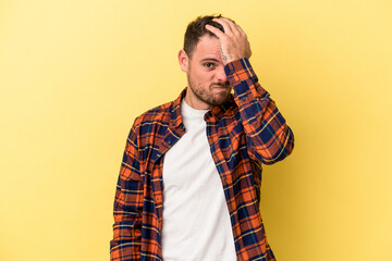 Young caucasian man isolated on yellow background forgetting something, slapping forehead with palm...