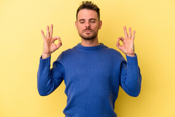 Fototapeta premium Young caucasian man isolated on yellow background relaxes after hard working day, she is performing yoga.