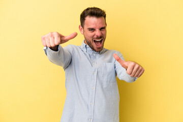 Young caucasian man isolated on yellow background raising both thumbs up, smiling and confident.