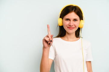 Young English woman listening to music isolated on blue background showing number one with finger.