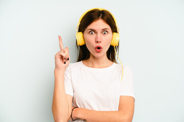 Young English woman listening to music isolated on blue background having some great idea, concept of creativity.