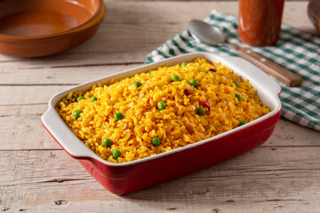 Traditional Mexican rice served with green peas on wooden table