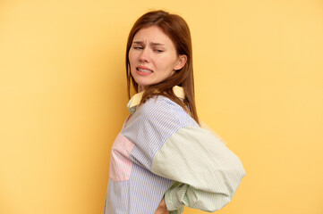 Young English woman isolated on yellow background suffering a back pain.