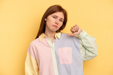 Young English woman isolated on yellow background showing a dislike gesture, thumbs down....
