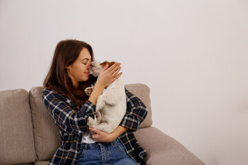 Portrait of young beautiful woman playing with her adorable four months old wire haired Jack Russel terrier puppy. Loving girl with rough coated pup having fun. Background, close up, copy space.