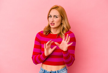 Young caucasian woman isolated on pink background rejecting someone showing a gesture of disgust.