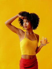 beautiful young African american woman in bright summer outfit drinking refreshing cocktail...