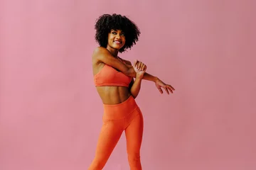 Foto op Plexiglas beautiful smiling young fit woman in sportswear stretching isolated on pink background © Carlos David