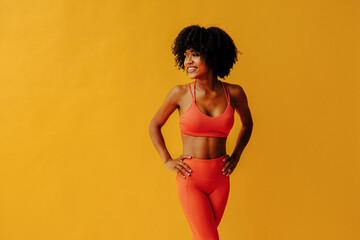 young fit woman in sportswear posing isolated on yellow background - obrazy, fototapety, plakaty
