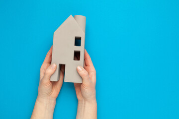 Selling or buying real estate. House miniature in hands on a blue background.