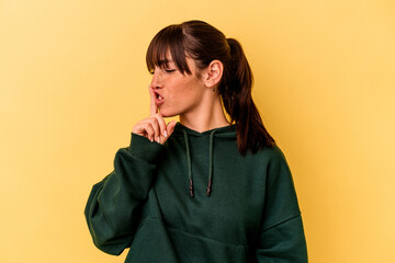Young Argentinian woman isolated on yellow background keeping a secret or asking for silence.