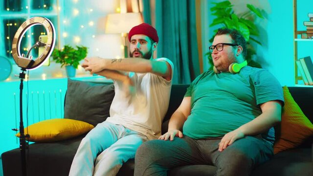 Dancing funny two friends one of them are big on the sofa and recording on the smartphone using a light ring. Shot on ARRI Alexa