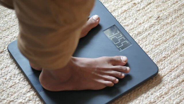  young man's feet on weight scale top view 