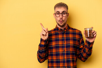 Fototapeta premium Young caucasian man holding a almond jar isolated on yellow background pointing to the side