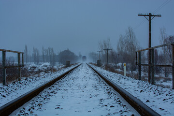View of the train track while it's snowing, a train away. - Powered by Adobe